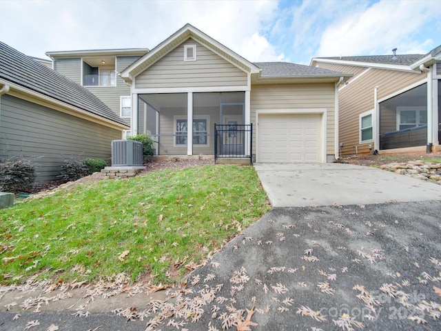 view of front property with a sunroom, cooling unit, a garage, and a front lawn