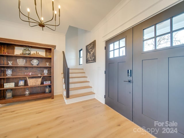 foyer entrance featuring a chandelier, light hardwood / wood-style floors, and crown molding