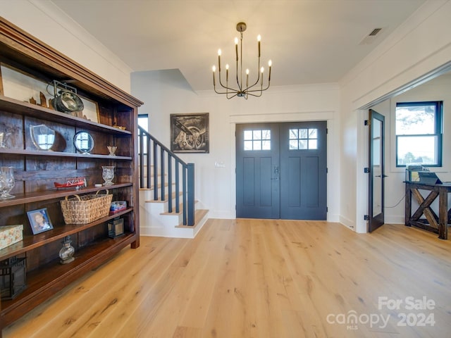 foyer entrance with a chandelier, crown molding, and light hardwood / wood-style flooring