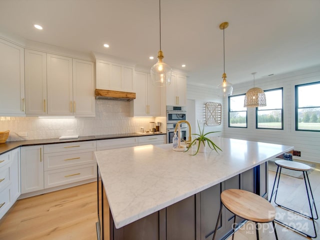 kitchen featuring pendant lighting, white cabinets, and an island with sink