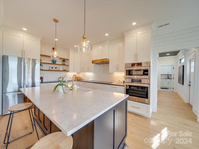 kitchen featuring sink, white cabinetry, a kitchen island with sink, and appliances with stainless steel finishes