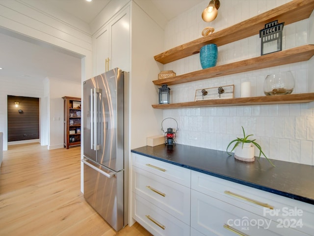 kitchen with white cabinets, tasteful backsplash, light wood-type flooring, and high end refrigerator