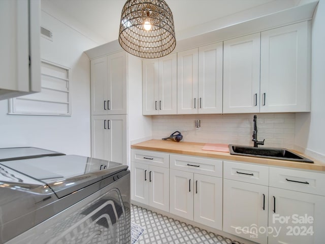 kitchen with sink, wood counters, independent washer and dryer, decorative backsplash, and white cabinets