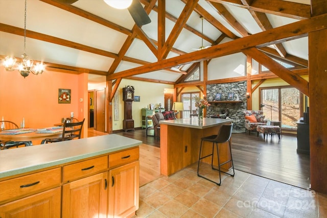 kitchen featuring light wood-type flooring, decorative light fixtures, vaulted ceiling with beams, and a center island