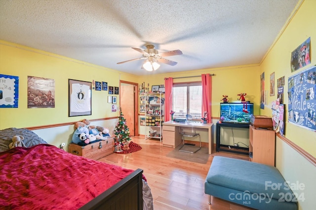 bedroom with ceiling fan, light hardwood / wood-style flooring, crown molding, and a textured ceiling