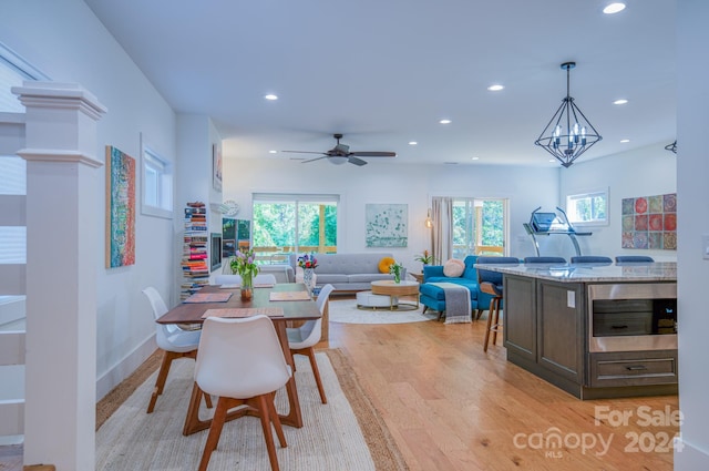 dining space featuring plenty of natural light, ceiling fan with notable chandelier, and light hardwood / wood-style flooring