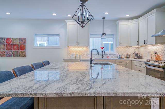 kitchen with gas range, white cabinetry, a chandelier, a breakfast bar area, and a kitchen island