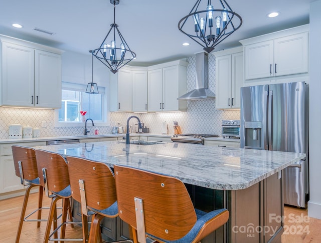 kitchen featuring white cabinetry, sink, wall chimney exhaust hood, stainless steel appliances, and a spacious island