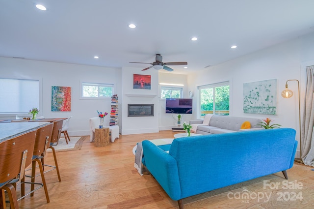 living room featuring light hardwood / wood-style flooring, ceiling fan, and a healthy amount of sunlight