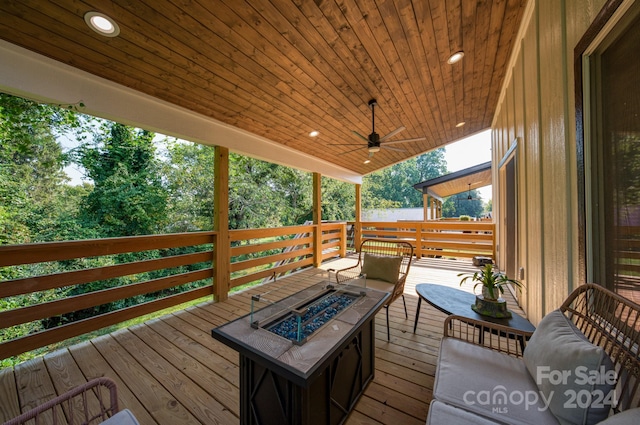 wooden deck with ceiling fan, a water view, and a fire pit