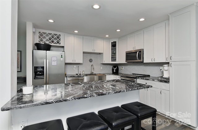 kitchen with white cabinetry, stainless steel appliances, and dark stone counters