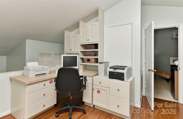 office area with vaulted ceiling, light hardwood / wood-style flooring, and a textured ceiling