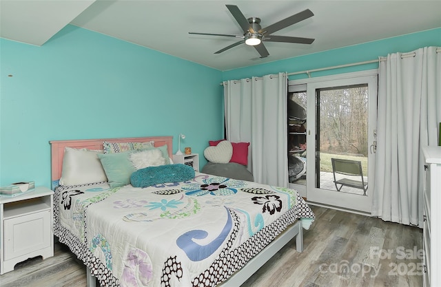 bedroom with multiple windows, access to exterior, wood-type flooring, and ceiling fan