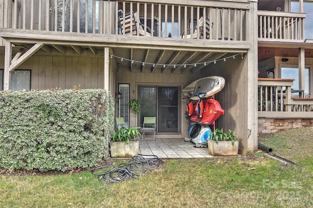 view of exterior entry with a lawn and a balcony