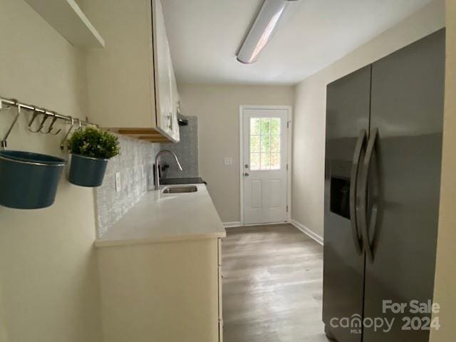 kitchen with decorative backsplash, stainless steel fridge, light hardwood / wood-style flooring, and sink