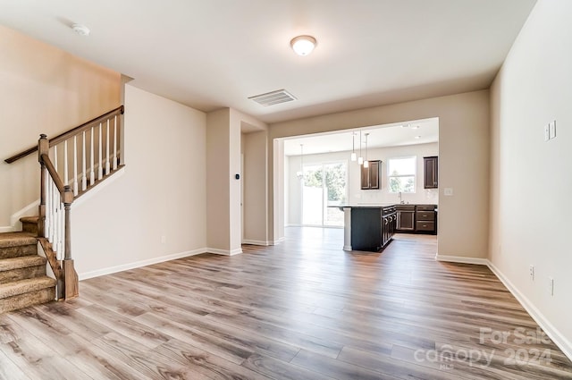 unfurnished living room featuring sink and light hardwood / wood-style floors