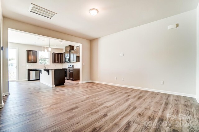 unfurnished living room with light wood-type flooring and sink