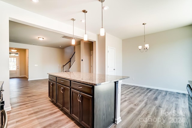 kitchen with dark brown cabinets, light wood-type flooring, and hanging light fixtures