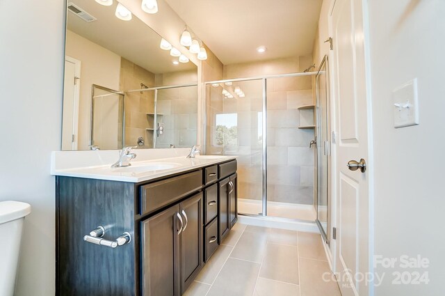 bathroom with tile patterned flooring, vanity, a shower with door, and toilet