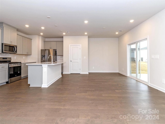 kitchen featuring decorative backsplash, dark hardwood / wood-style flooring, an island with sink, and stainless steel appliances