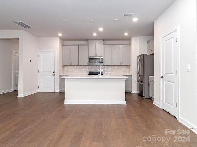 kitchen featuring gray cabinetry, dark hardwood / wood-style flooring, a kitchen island with sink, and appliances with stainless steel finishes