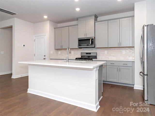 kitchen featuring gray cabinetry, a kitchen island with sink, stainless steel appliances, and dark hardwood / wood-style floors