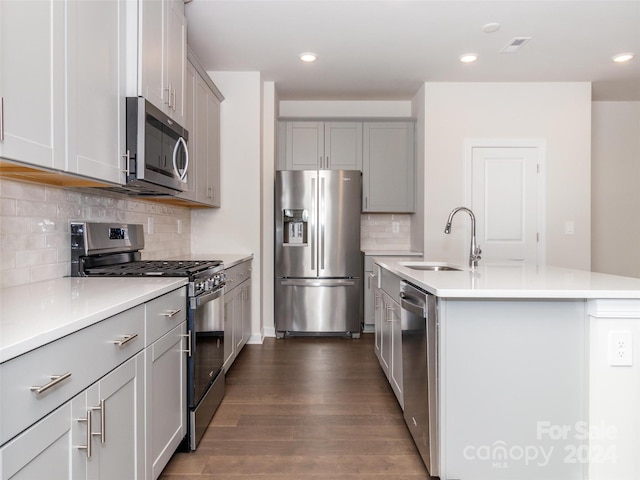 kitchen with backsplash, a center island with sink, sink, dark hardwood / wood-style flooring, and stainless steel appliances