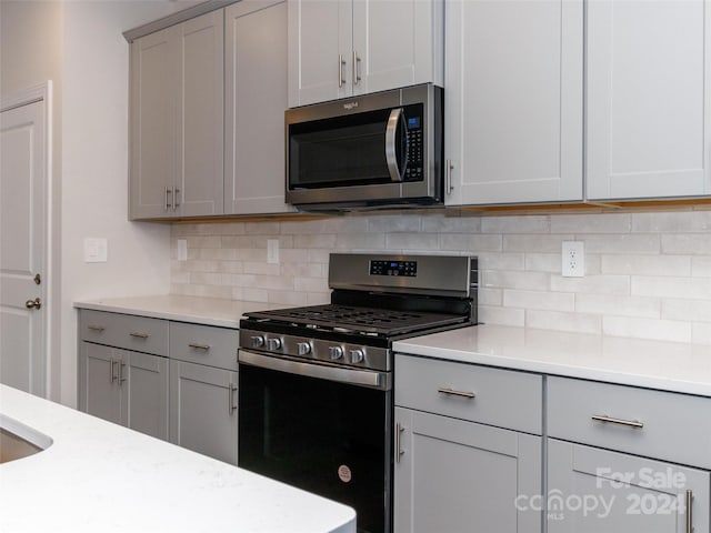 kitchen featuring backsplash, gray cabinetry, and appliances with stainless steel finishes