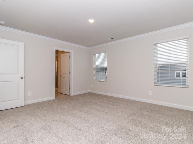 empty room featuring light colored carpet and crown molding