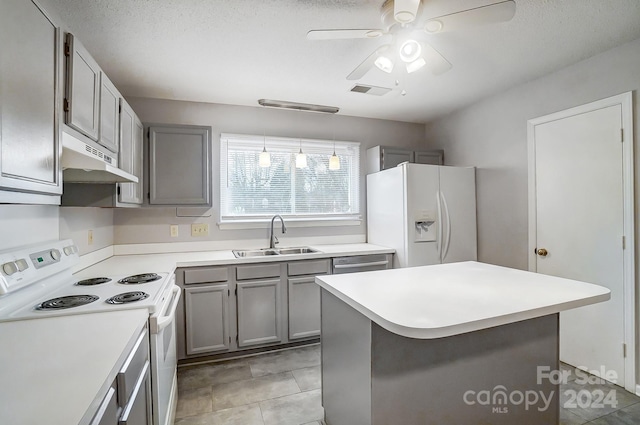 kitchen with a textured ceiling, decorative light fixtures, white appliances, and sink