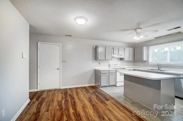 kitchen featuring sink, white electric range, hardwood / wood-style floors, gray cabinets, and a kitchen island