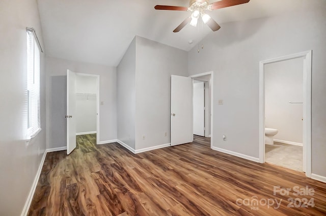 unfurnished bedroom featuring vaulted ceiling, ceiling fan, dark wood-type flooring, a spacious closet, and a closet