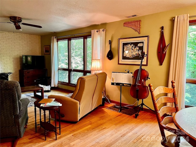 living room featuring ceiling fan, light hardwood / wood-style floors, and a textured ceiling