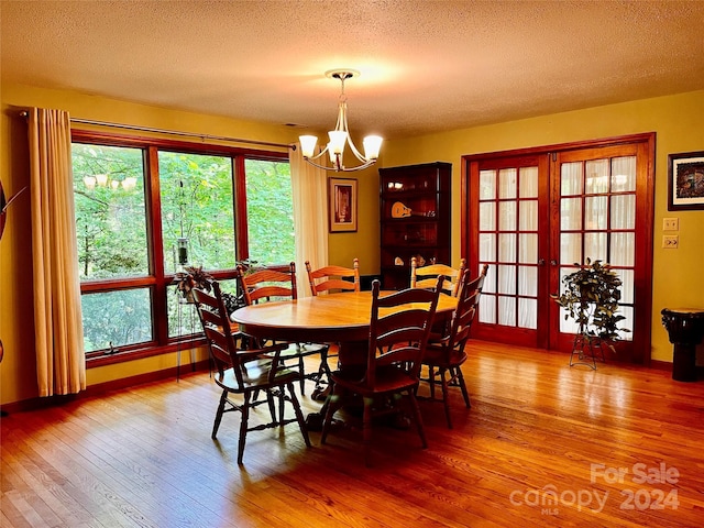 dining area with a chandelier, a textured ceiling, and hardwood / wood-style flooring