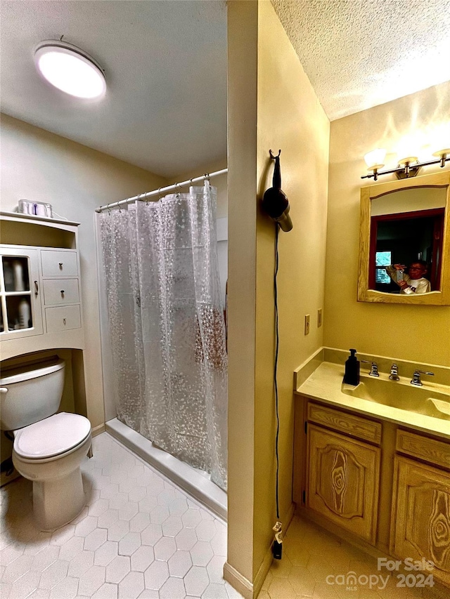 bathroom with vanity, tile patterned floors, a shower with curtain, toilet, and a textured ceiling