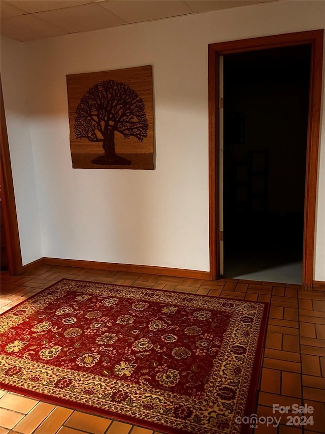 hallway featuring tile patterned floors and a drop ceiling