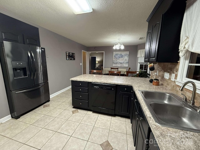 kitchen featuring sink, black dishwasher, backsplash, stainless steel fridge, and a chandelier