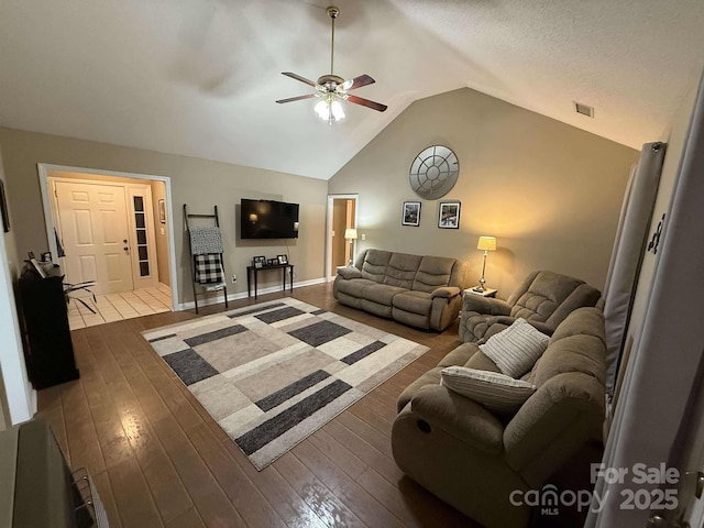 living room featuring hardwood / wood-style flooring, ceiling fan, and vaulted ceiling