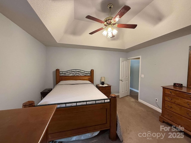 carpeted bedroom featuring ceiling fan and a tray ceiling