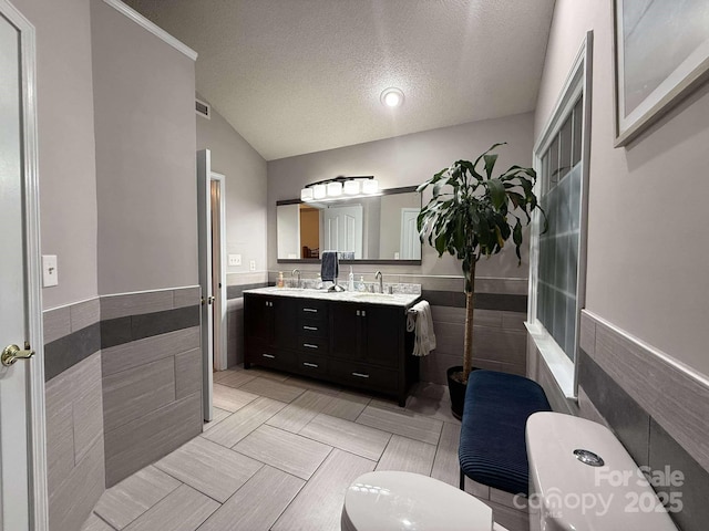 bathroom with tile walls, a textured ceiling, and vanity