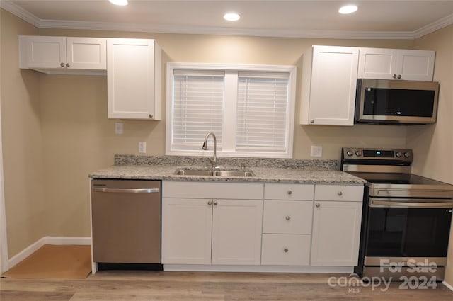 kitchen featuring white cabinets, appliances with stainless steel finishes, light stone counters, and sink