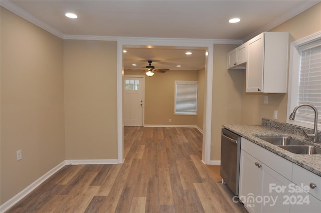 kitchen with light stone countertops, light wood-type flooring, stainless steel dishwasher, sink, and white cabinetry