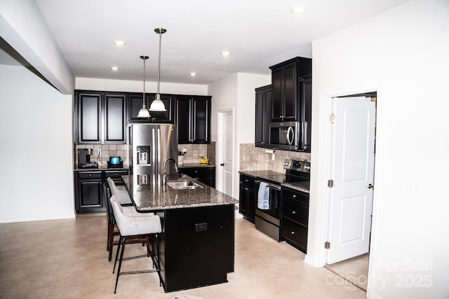 kitchen featuring a kitchen bar, appliances with stainless steel finishes, sink, a center island with sink, and decorative light fixtures