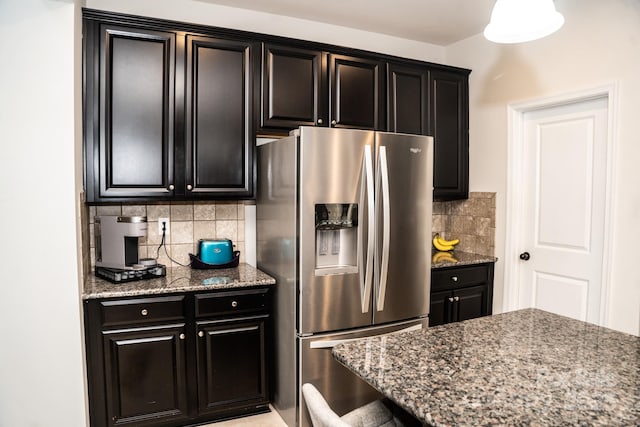 kitchen featuring stone counters, stainless steel fridge, and backsplash