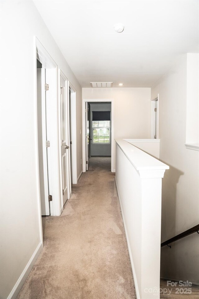 hallway featuring light colored carpet