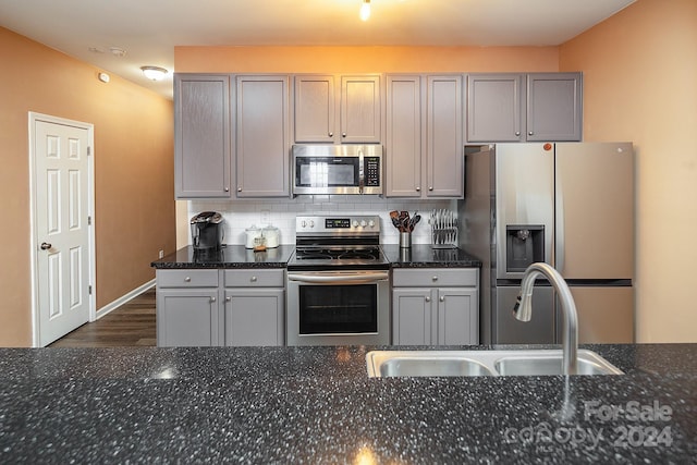 kitchen with dark stone counters, sink, appliances with stainless steel finishes, and tasteful backsplash