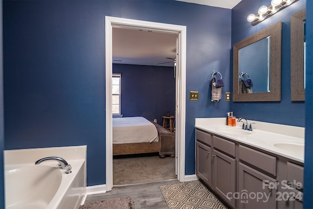 bathroom with ceiling fan, vanity, a bath, and hardwood / wood-style flooring