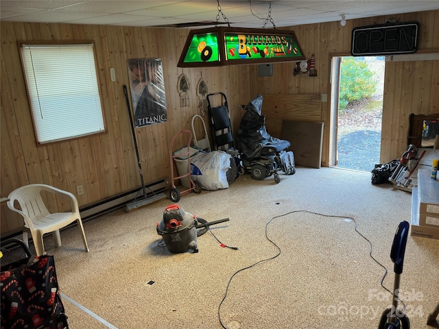 carpeted dining area featuring wood walls and a baseboard radiator