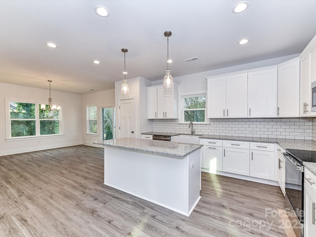 kitchen featuring light wood-style flooring, a sink, white cabinets, electric stove, and backsplash