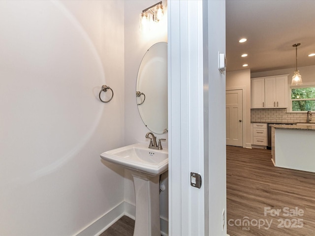 bathroom with wood finished floors, baseboards, recessed lighting, a sink, and backsplash